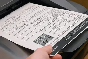 Despachante trabalhando na impressão do CRLV-e com documentos na mesa.